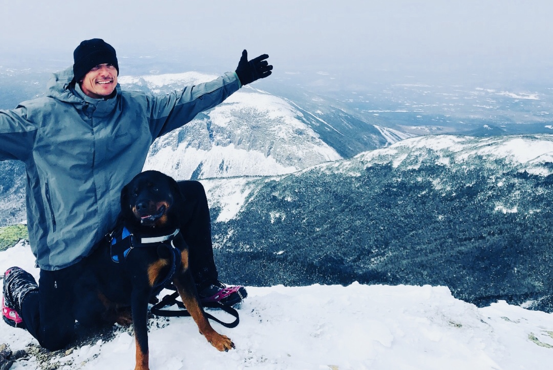 Trainer Blake Vonasek with a Rottweiler on a snowy New Hampshire mountain
